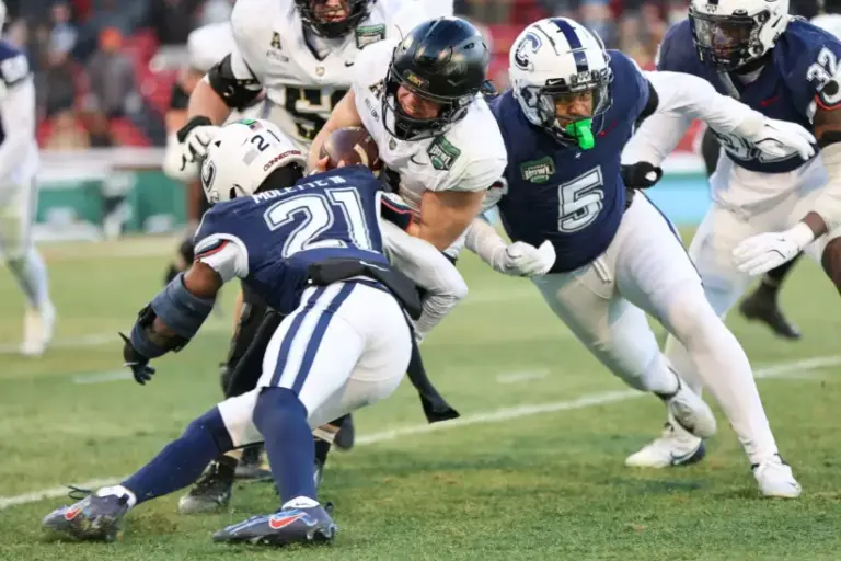 Army's Cale Hellums is tackled by UConn's Lee Molette III and Aaron Key during the Fenway Bowl at Fenway Park in Boston on Saturday, Dec. 27, 2025.