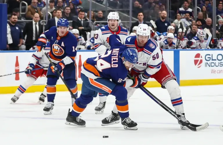 Dec 27, 2025; Elmont, New York, USA; New York Islanders defenseman Scott Mayfield (24) and New York Rangers left wing Will Cuylle (50) battle for control of the puck in the third period at UBS Arena.