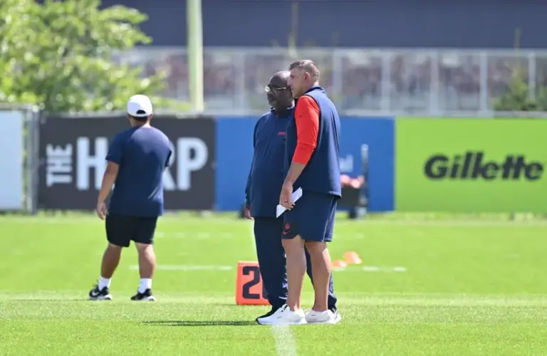 New England Patriots head coach Mike Vrabel (red sleeves) and defensive coordinator Terrell Williams watch players during training camp at Gillette Stadium.