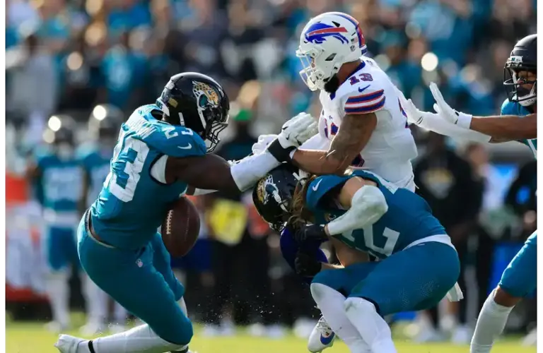 Buffalo Bills wide receiver Gabe Davis (13), center, can’t haul in a reception against Jacksonville Jaguars safety Andrew Wingard (42), bottom, and linebacker Foyesade Oluokun (23), left, during the fourth quarter of an NFL football AFC Wild Card playoff matchup, Sunday, Jan. 11, 2026, in Jacksonville, Fla. The Bills defeated the Jaguars 27-24.