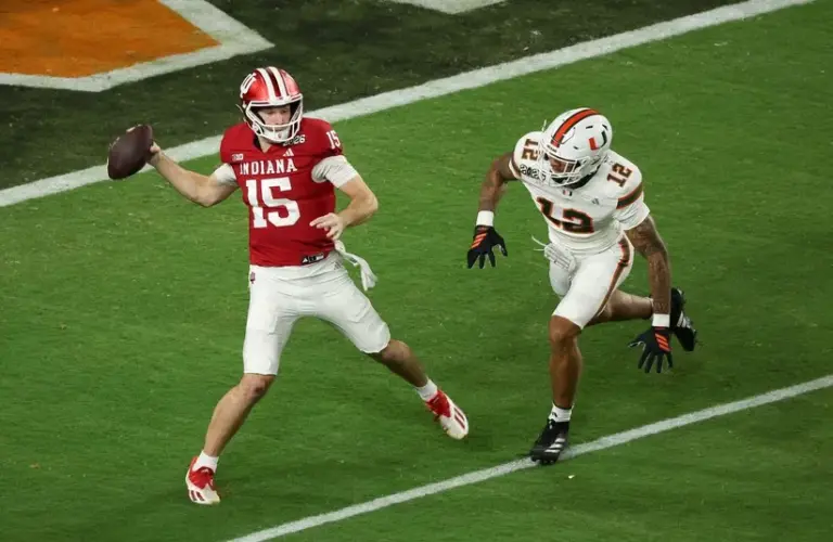 Indiana Hoosiers quarterback Fernando Mendoza (15) passes the ball under pressure by Miami Hurricanes defensive lineman Marquise Lightfoot (12) in the first quarter during the College Football Playoff National Championship game at Hard Rock Stadium