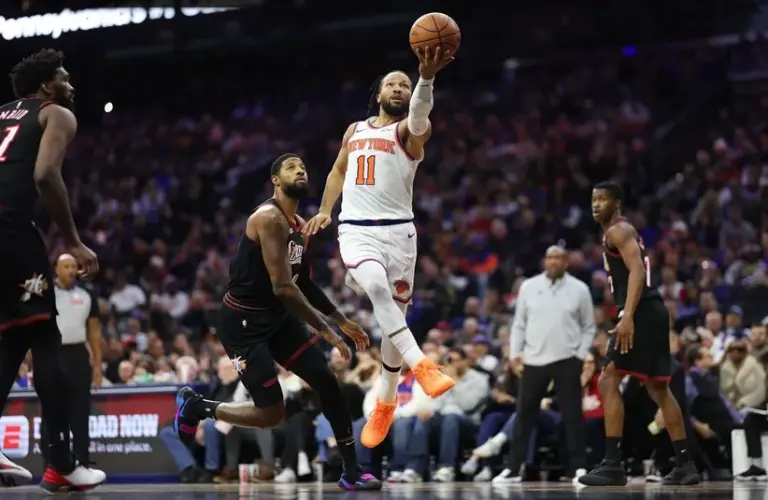 New York Knicks guard Jalen Brunson (11) drives for a score past Philadelphia 76ers forward Paul George (8) during the second quarter at Xfinity Mobile Arena.