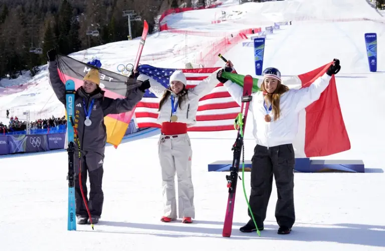February 8, 2026; Cortina d'Ampezzo, Italy; From left Emma Aicher of Germany, Breezy Johnson of the United States and Sofia Goggia of Italy celebrate after the women's downhill alpine skiing race during the Milano Cortina 2026 Olympic Winter Games at Alpine Skiing.