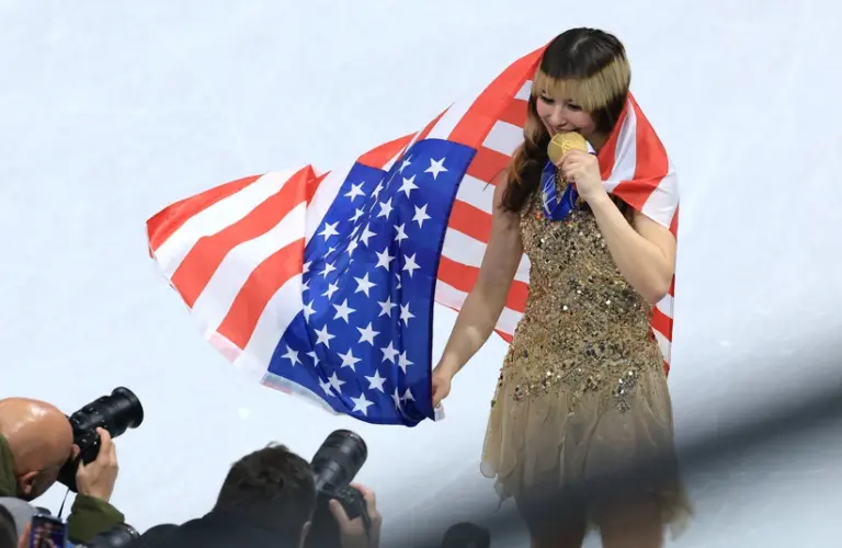 Feb 19, 2026; Milan, Italy; Alysa Liu of the United States celebrates with the gold medal and the flag after the medal ceremony for the women's free skate during the Milano Cortina 2026 Olympic Winter Games at Milano Ice Skating Arena.
