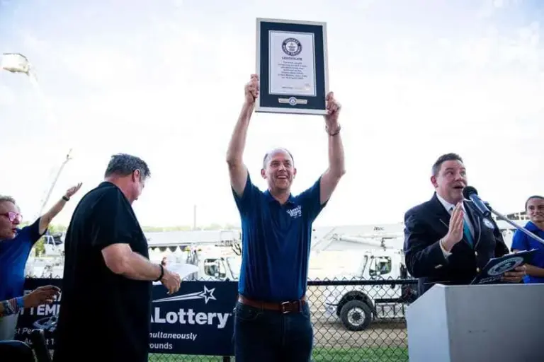 NASCAR; Iowa Lottery CEO Matt Strawn holds up the plaque for most people simultaneously scratching off a lottery ticket on Aug. 14, 2025, at the Iowa State Fair in Des Moines.