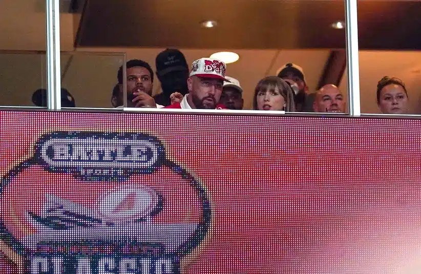 Taylor Swift looks on with Travis Kelce.
