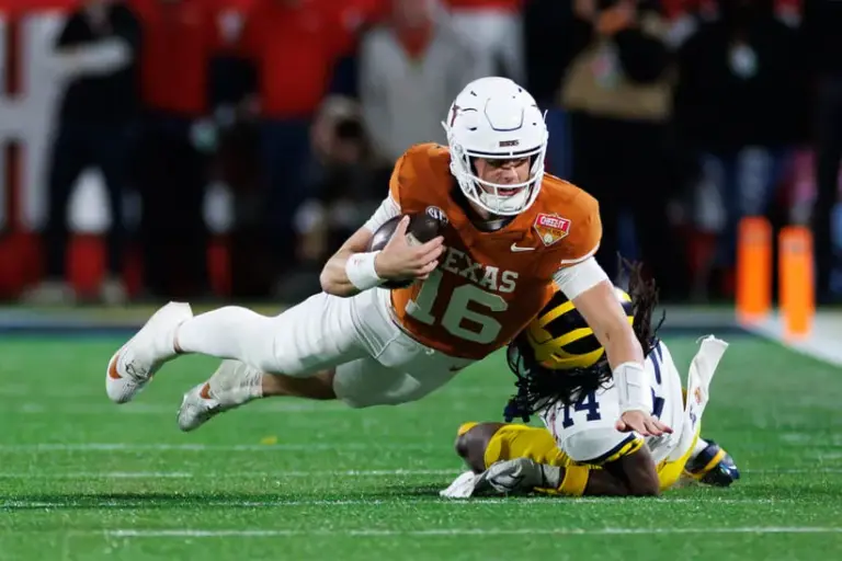 Caption: Dec 31, 2025; Orlando, FL, USA; Texas Longhorns quarterback Arch Manning (16) dives forward over Michigan Wolverines defensive back Jordan Young (14) during the second half at Camping World Stadium.