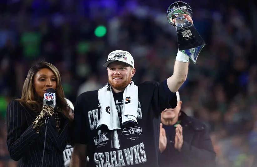 Seattle Seahawks quarterback Sam Darnold (14) celebrates with the Vince Lombardi trophy on the podium after defeating the New England Patriots in Super Bowl LX at Levi's Stadium.
