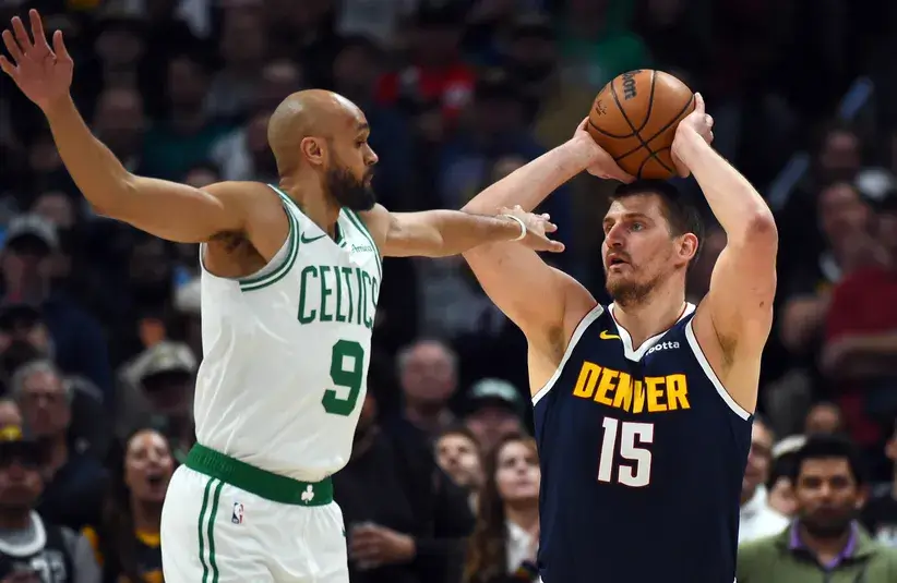 Denver Nuggets center Nikola Jokic (15) looks to pass the ball as he is defended by Boston Celtics guard Derrick White (9) during the first half.
