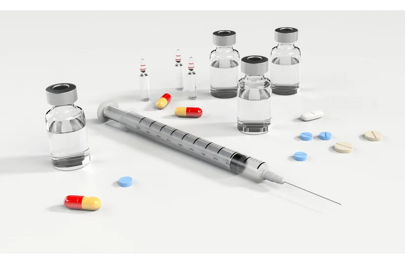 Syringe and various medications, including capsules, tablets, and vials, are arranged on a plain surface, conveying a medical theme. WADA responds to rumors of HA use among male ski jumpers at the 2026 Winter Olympics.