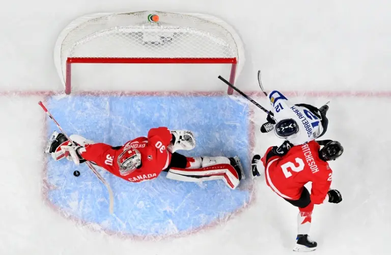 Jan 5, 2026; St. Paul, Minnesota, USA; Canada goalie Carter George (30) makes a save as defensemen Kashawn Aitcheson (2) and Finland forward Roope Vesterinen (12) battle for position during the third period in the third place game of the 2026 IIHF World Junior Championship ice hockey tournament at Grand Casino Arena.