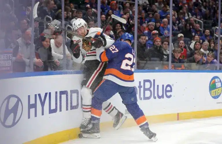 Mar 24, 2026; Elmont, New York, USA; New York Islanders left wing Anders Lee (27) checks Chicago Blackhawks defenseman Sam Rinzel (6) into the boards during the third period at UBS Arena.