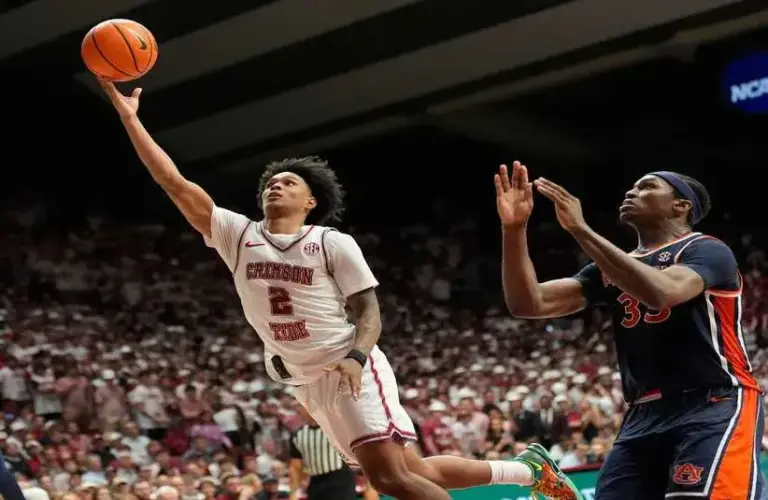 Alabama guard Aden Holloway (2) goes into the paint for a shot past Auburn forward Sebastian Williams-Adams (33).
