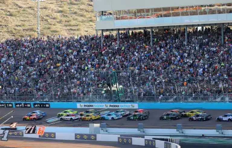Nov 2, 2025; Avondale, Arizona, USA; Overall view of the fans in the front stretch grandstands as NASCAR Cup Series driver William Byron (24) and Denny Hamlin (11) lead the field on a restart during the NASCAR Championship race at Phoenix Raceway.