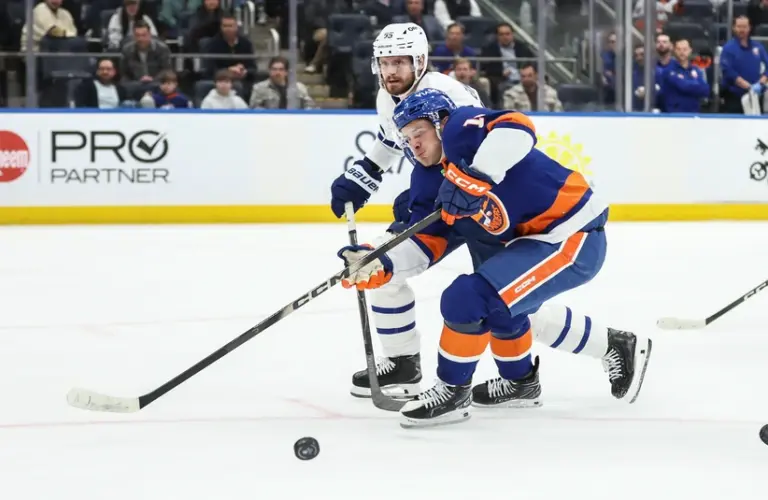 Apr 9, 2026; Elmont, New York, USA; Toronto Maple Leafs defenseman Oliver Ekman-Larsson (95) and New York Islanders center Mathew Barzal (13) battle for control of the puck in the second period at UBS Arena.