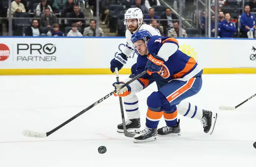 Apr 9, 2026; Elmont, New York, USA; Toronto Maple Leafs defenseman Oliver Ekman-Larsson (95) and New York Islanders center Mathew Barzal (13) battle for control of the puck in the second period at UBS Arena.