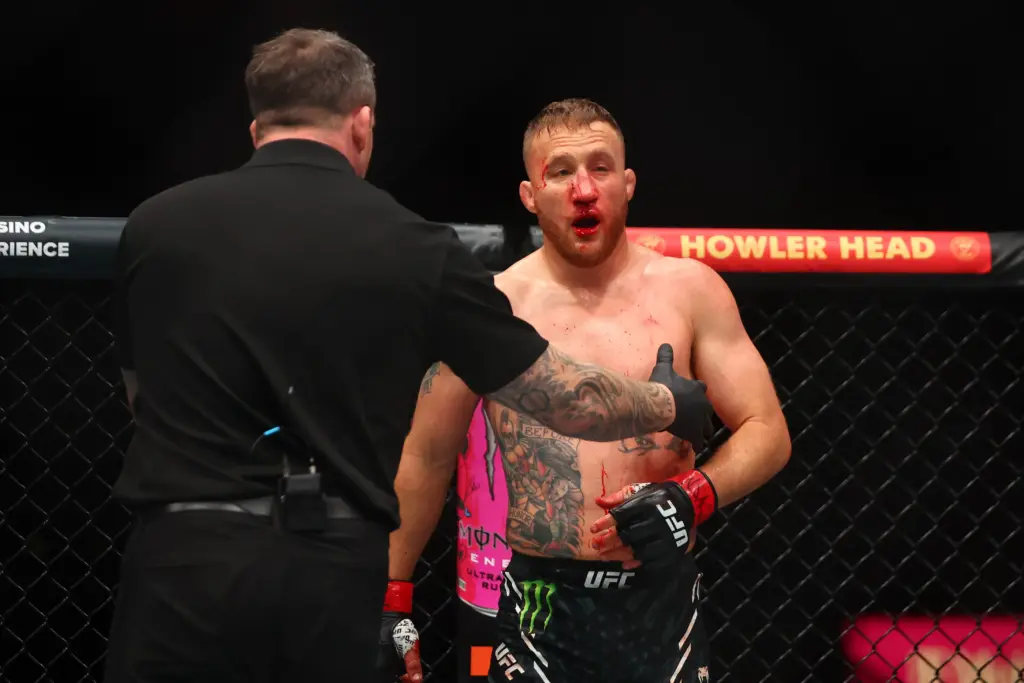 Justin Gaethje (red gloves) is helped to the corner of the cage.