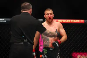 Justin Gaethje (red gloves) is helped to the corner of the cage.