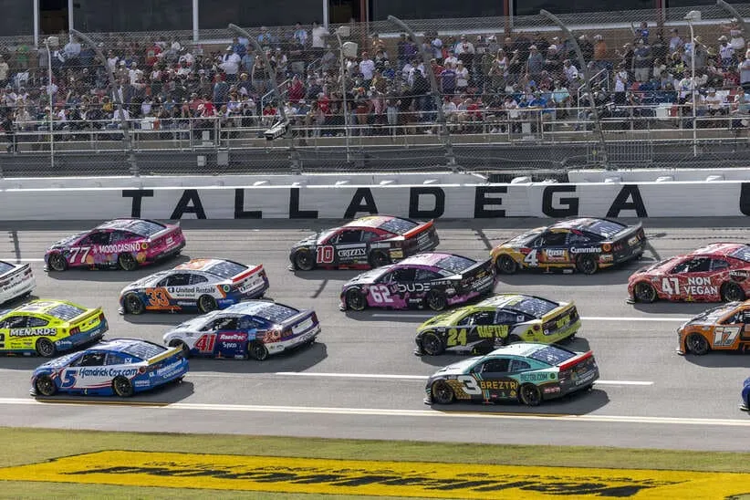 Oct 19, 2025; Talladega, Alabama, USA; Cars race by Talladega signage during stage one of the YellaWood 500 at Talladega Superspeedway.