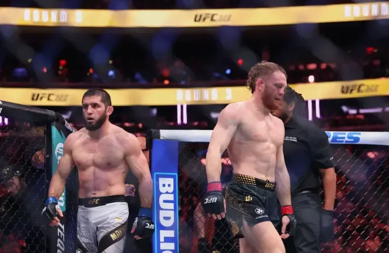 Islam Makhachev (blue gloves) and Jack Della Maddalena (red gloves) walk to their corners.