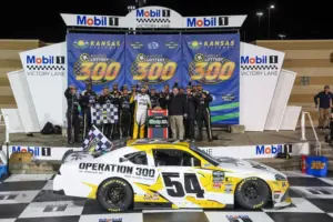 Apr 18, 2026; Kansas City, Kansas, USA; NASCAR O’Reilly Auto Parts Series driver Taylor Gray (54) poses with his team after winning the Kansas Lottery 300 at Kansas Speedway.