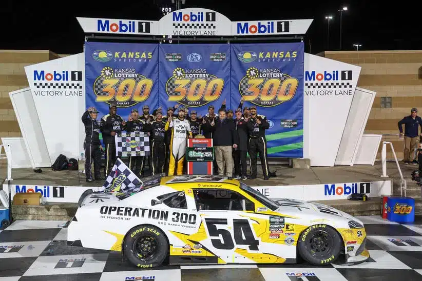 Apr 18, 2026; Kansas City, Kansas, USA; NASCAR O’Reilly Auto Parts Series driver Taylor Gray (54) poses with his team after winning the Kansas Lottery 300 at Kansas Speedway.
