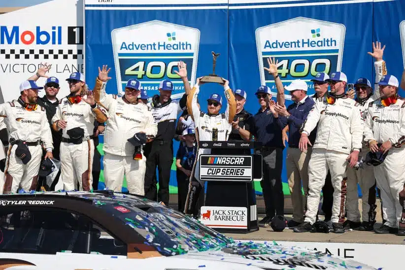 Apr 19, 2026; Kansas City, Kansas, USA; NASCAR Cup Series driver Tyler Reddick (45) holds up the winner’s trophy after winning the AdventHealth 400 at Kansas Speedway.