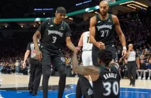 Minnesota Timberwolves center Rudy Gobert (27) and forward Jaden McDaniels (3) help up forward Julius Randle (30).