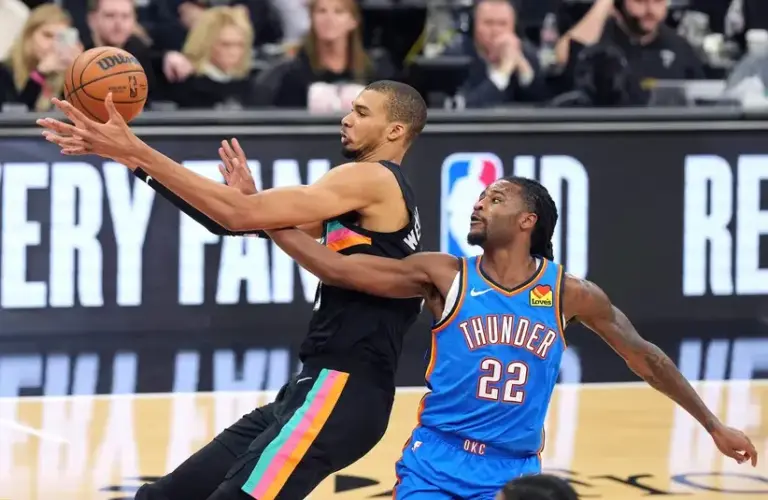 San Antonio Spurs center Victor Wembanyama (1) and Oklahoma City Thunder guard Cason Wallace (22) battle for a loose ball during the first half.