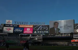 The main scoreboard displays a message honoring John Sterling, the Yankees radio play-by-play announcer.