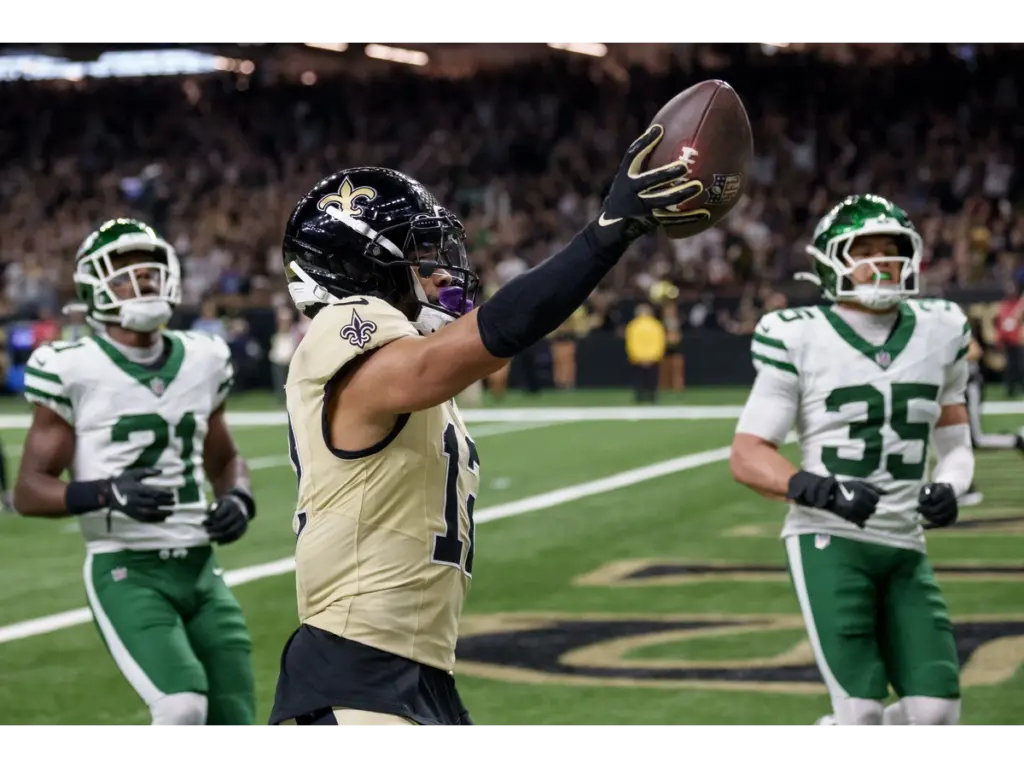 Dec 21, 2025; New Orleans, Louisiana, USA; New Orleans Saints wide receiver Chris Olave (12) crosses the goal line for a touchdown against New York Jets cornerback Brandon Stephens (21) and safety Dean Clark (35) during the third quarter at Caesars Superdome. Mandatory Credit: Matthew Hinton-Imagn Images