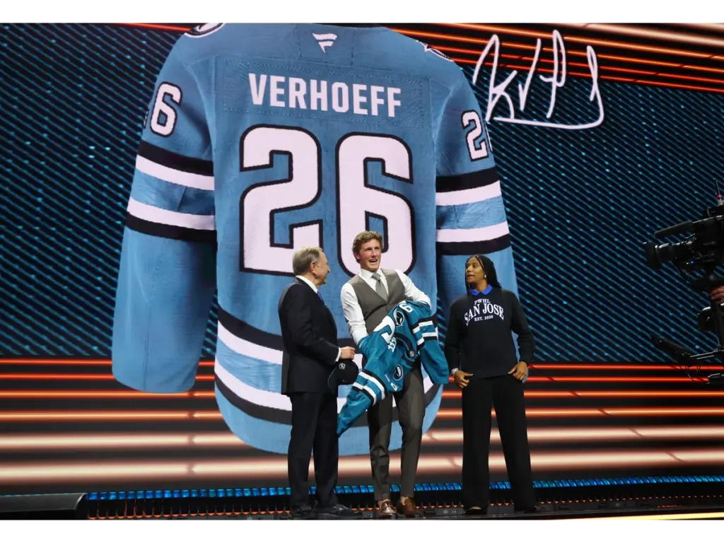 Jun 26, 2026; Buffalo, New York, USA; Keaton Verhoeff reacts beside NHL commissioner Gary Bettman and PWHL San Jose player Laila Edwards after being selected with the ninth pick in the first round of the 2026 NHL Draft by the San Jose Sharks at KeyBank Center. Mandatory Credit: Timothy T. Ludwig-Imagn Images