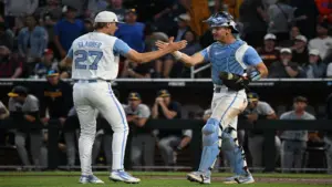 Jun 14, 2026; Omaha, NE, USA; North Carolina Tar Heels pitcher Caden Glauber (27) and catcher Colin Hynek (23) celebrate the win against the West Virginia Mountaineers at Charles Schwab Field.