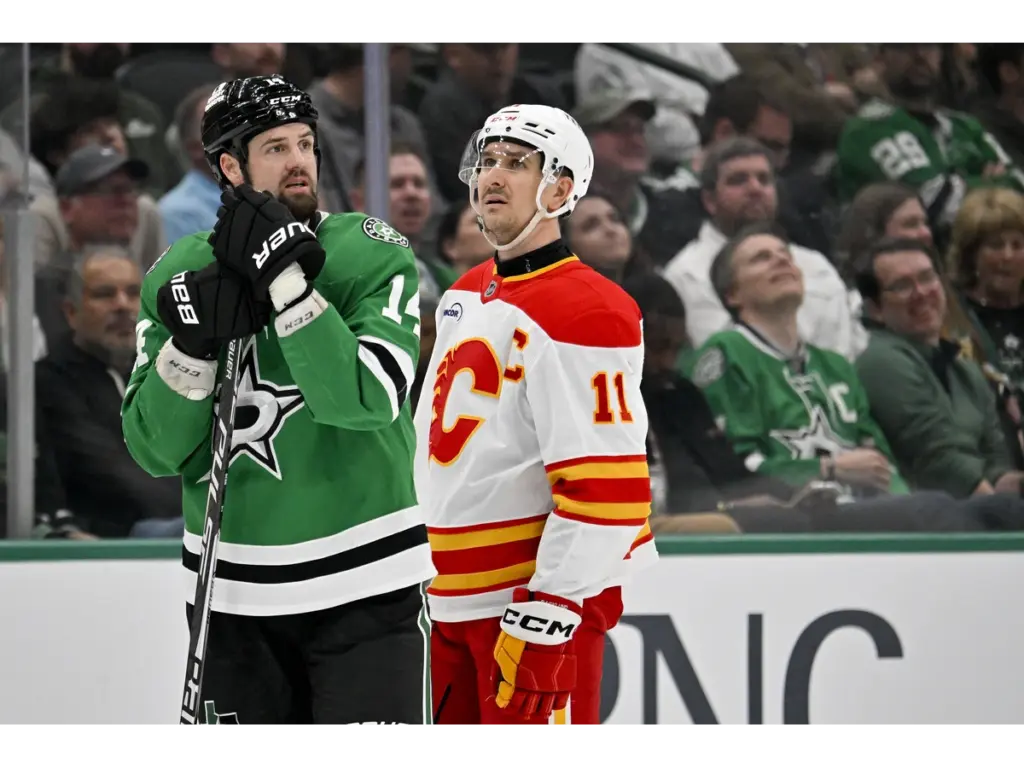 Apr 7, 2026; Dallas, Texas, USA; Dallas Stars left wing Jamie Benn (14) and Calgary Flames center Mikael Backlund (11) look on as the referees check the replay of a hit by defenseman Tyler Myers (not pictured) during the third period at the American Airlines Center. Mandatory Credit: Jerome Miron-Imagn Images