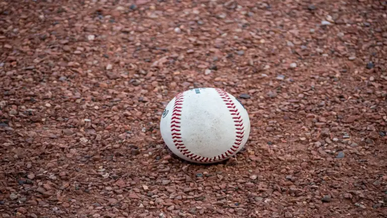 A close-up photograph of a baseball resting on a gravel surface, capturing the texture and detail. This is the instrument of Gerrit Cole's trade with the Yankees.